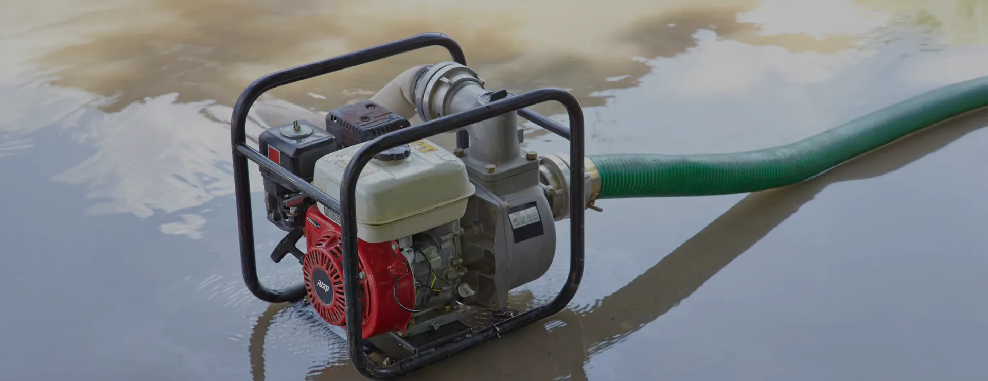 ALAP engine-driven water pump with delivery hose beside a water channel